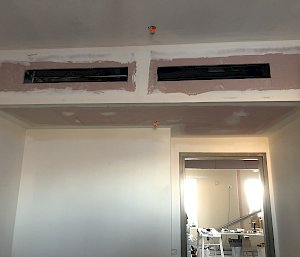 unpainted plaster wall with openings for air conditioning ducting