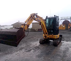 A small yellow telehandler with the bucket raised