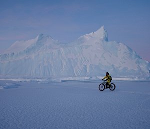 An expeditioner riding a bike across the ice and snow in Antarctica