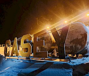 Big letters spelling out 'CASEY' stand in front of oil tanks, covered in snow.