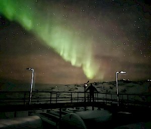 Shimmering green in the sky over a person standing on a bridge