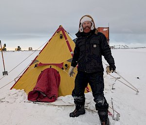 Man standing in front of tent on snow