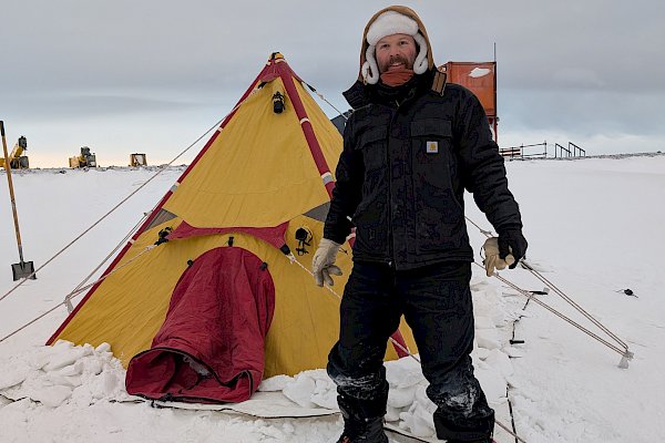 Man standing in front of tent on snow