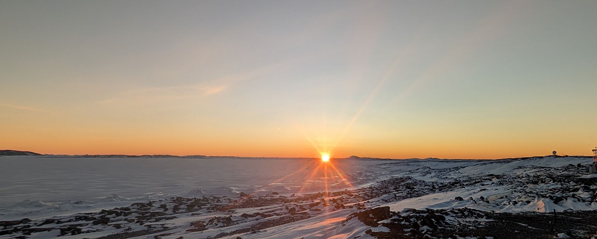 Sun rising on the horizon over frozen sea ice
