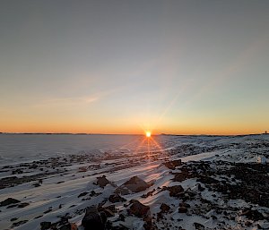 Sun rising on the horizon over frozen sea ice