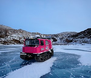 Hagglund parked on frozen lake with hills in background