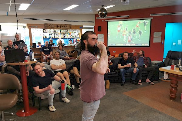 A man standing in front of a crowd with his arm pulled back, ready to throw a dart.
