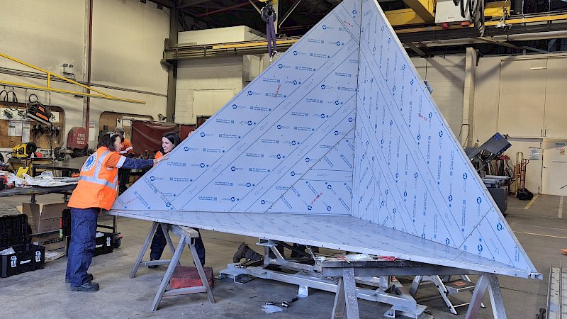 A triangular metal radar reflector being assembled in a workshop