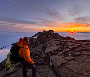 An expeditioner climbing a mountain in Antarctica