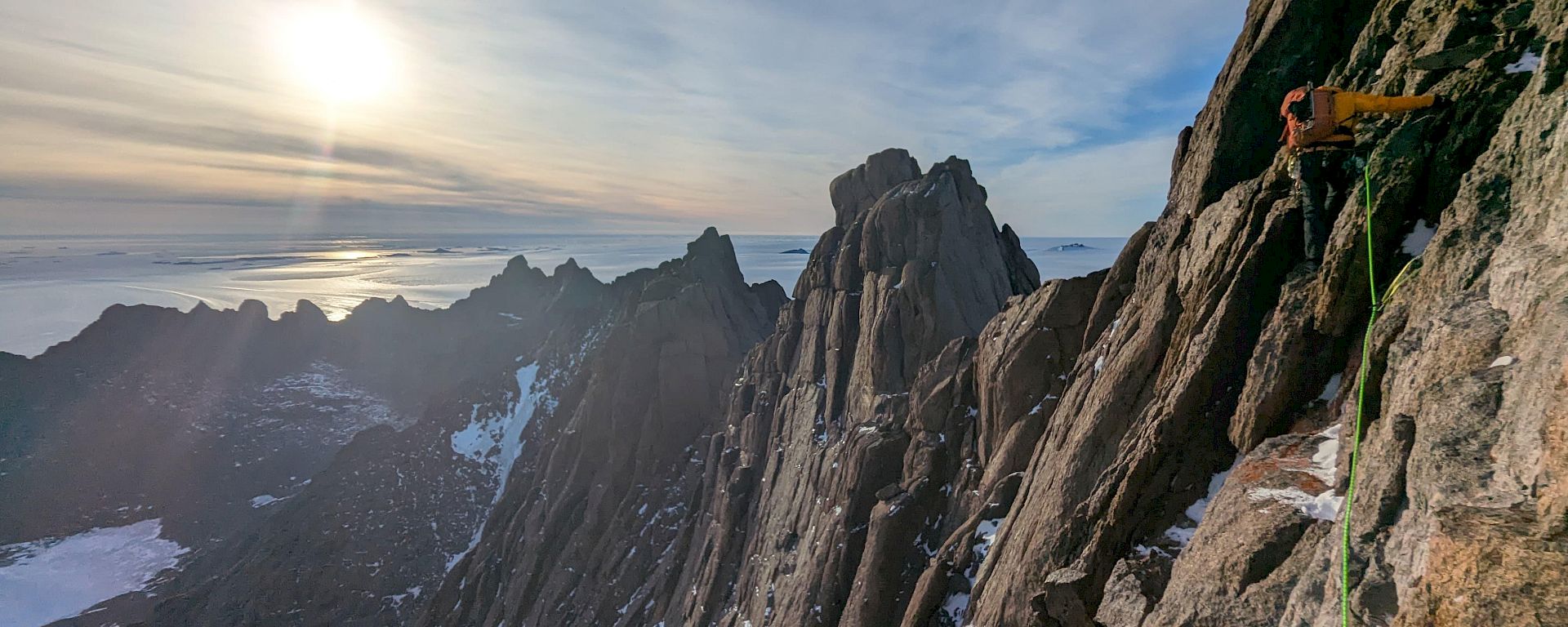 An expeditioner rock climbing on a mountain in Antarctica