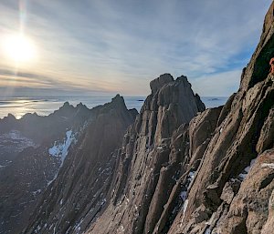 An expeditioner rock climbing on a mountain in Antarctica