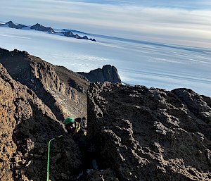 An expeditioner rock climbing on a mountain in Antarctica