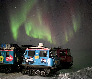 aurora in night sky with two vehicles in foreground
