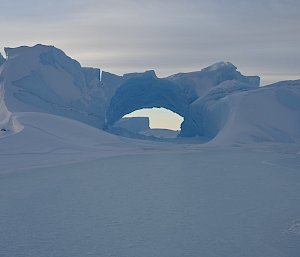 iceberg with tunnel and arch in middle