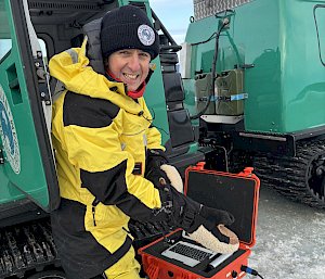 An expeditioner holding a piece of scientific equipment
