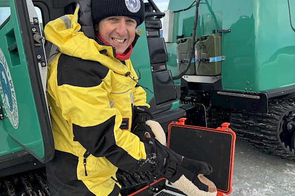 An expeditioner holding a piece of scientific equipment