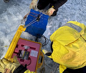 An expeditioner holding a piece of scientific equipment