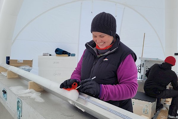 A woman marks the end of an ice core with a pencil.