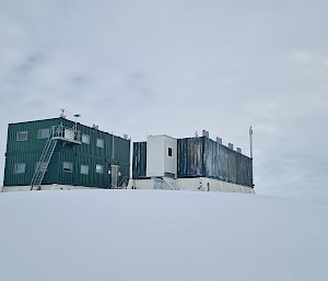 Two green buildings perched on the snow