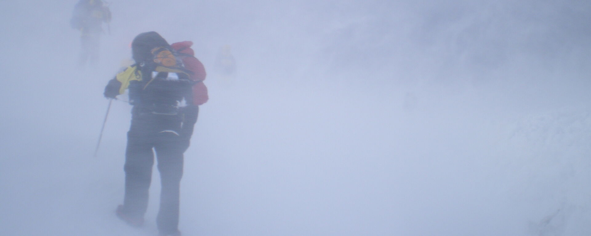 Two expeditioners, outside and barely visible in a blizzard