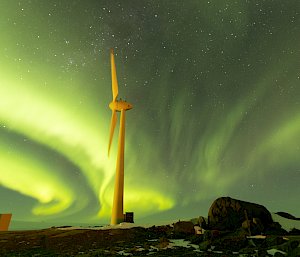 The night sky with auroras in Antarctica and a wind turbine in the foreground