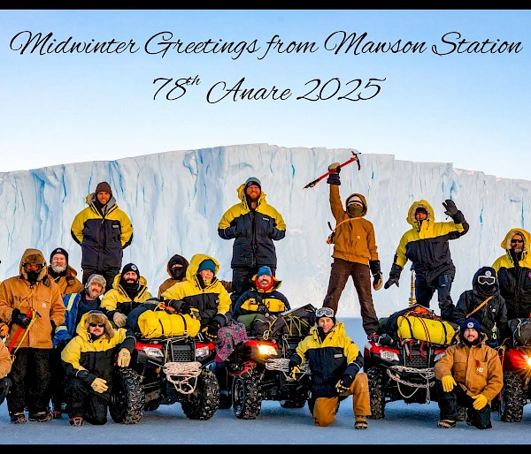 Group photo of the Mawson team on the sea ice, arranged around four quad vehicles