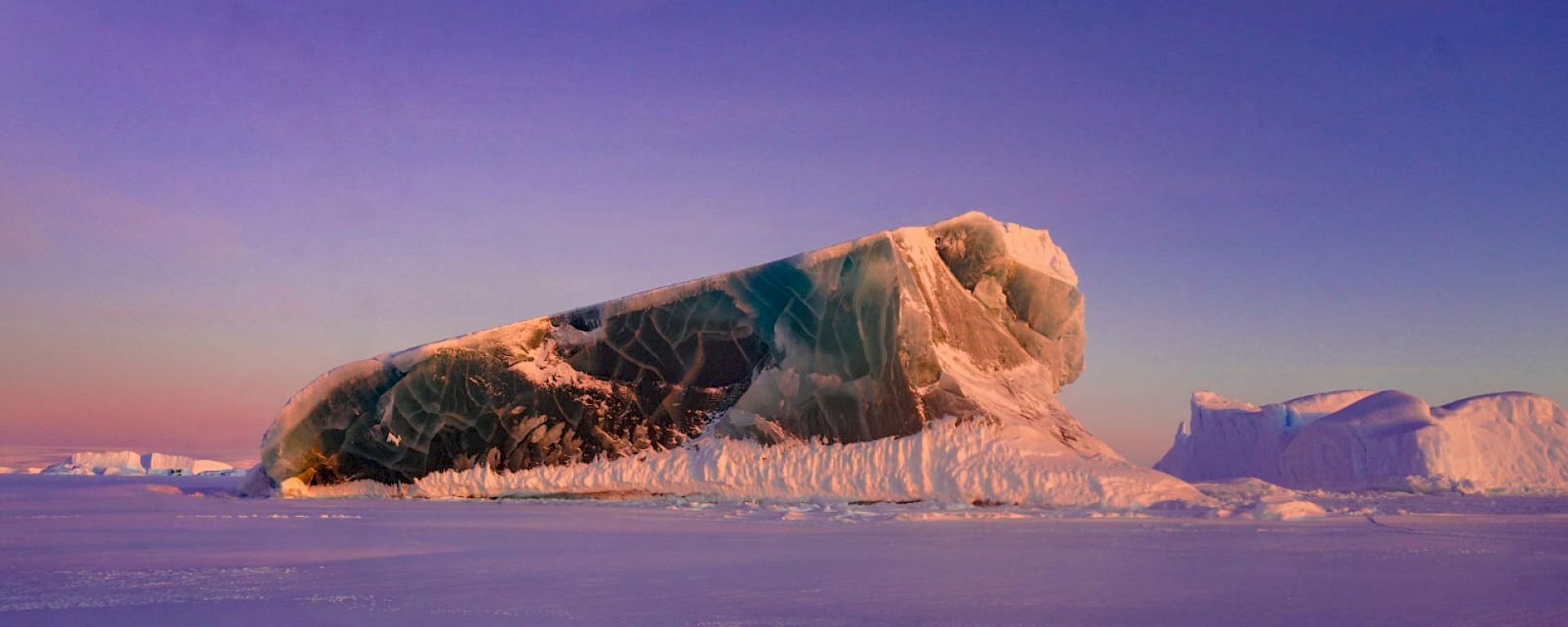 A jade iceberg rising above sea ice