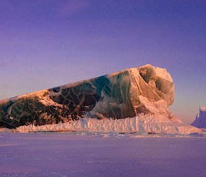 A jade iceberg rising above sea ice