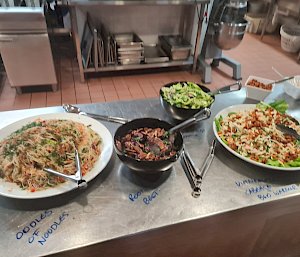 Two plates and two bowls of different salad