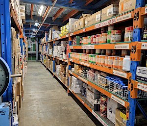 Shelves lined with tins, carboard boxes and wire racks filled with food