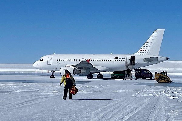 Expeditioner walking off plane parked on the ice