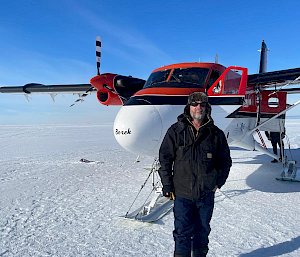 An expeditioner standing next to a small aircraft