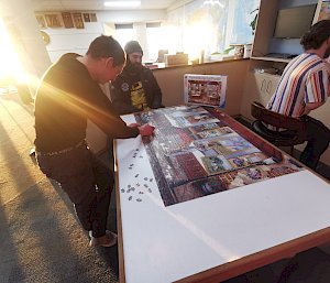 Expeditioners doing puzzles and playing board games in the Red Shed