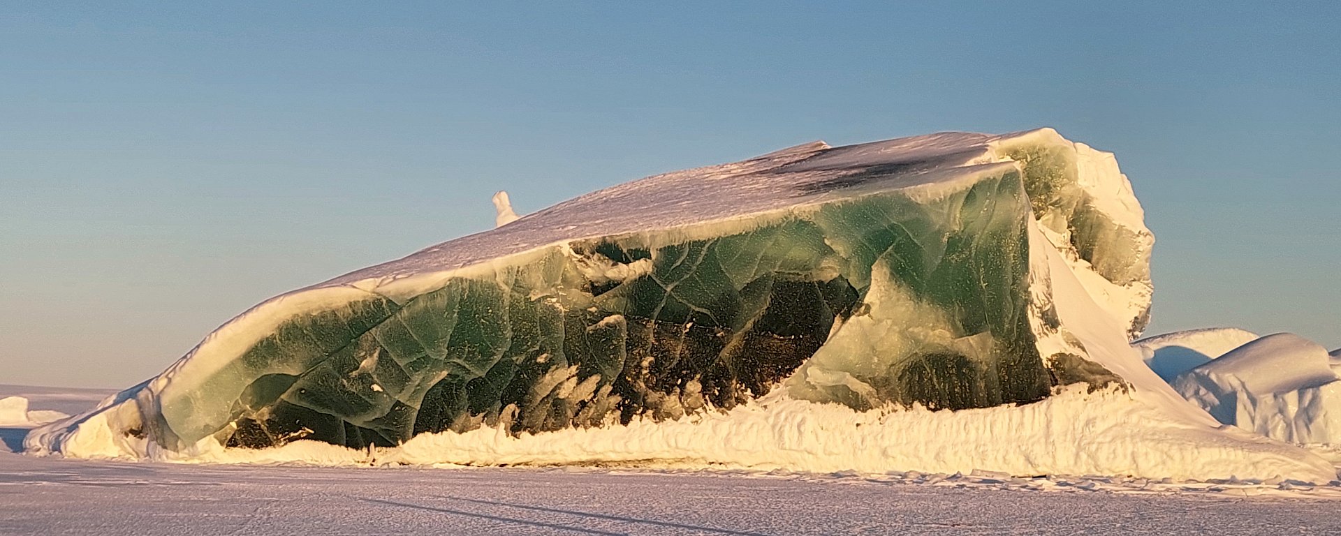 A jade-coloured iceberg rising out of sea ice