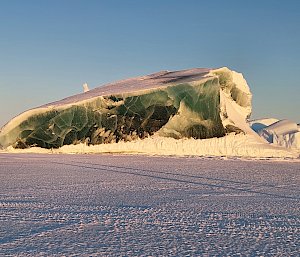 A jade-coloured iceberg rising out of sea ice