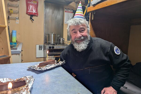 An expeditioner with a party hat inside the accommodation van celebrating his birthday