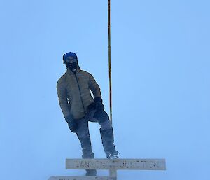 An expeditioner standing next to a cane dressed in heavy winter gear