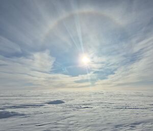 Photo of the sun with a ring around it, above the ice