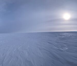 Landscape photo of the snow and ice with the sun showing through some cloud