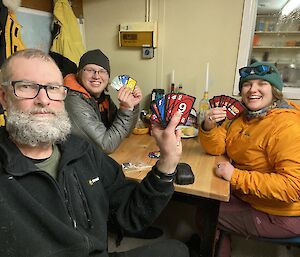 people sitting around table playing a card game