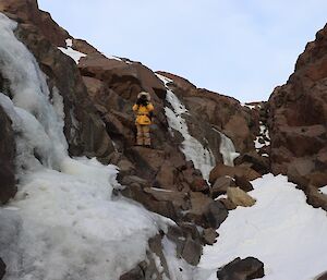 person standing next to a frozen waterfall