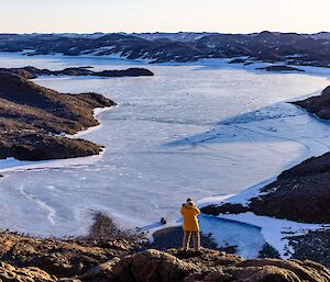 man taking photo of hills and fjord