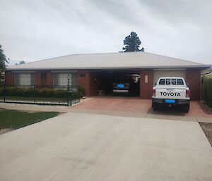 A suburban brick and colourbond house with a 4WD parked in the front driveway
