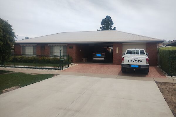 A suburban brick and colourbond house with a 4WD parked in the front driveway