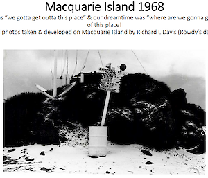 A black and white photo of a sign in a metal drum on a beach. The sign points to different cities around the world.