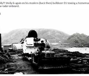 A man on a bulldozer towing a radar, on Macquarie Island.