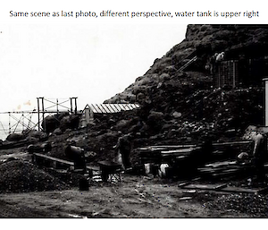 A black and white photo of a construction site, showing piles of dirt and gravel, and pieces of timber.