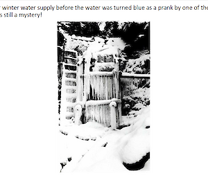 A black and white photo of icicles and snow flowing down a gully