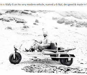 A black and white photo of a man sitting on a three-wheeled bike.