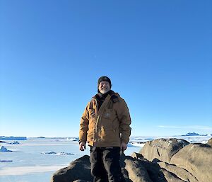 Dominik standing on a rocky outcrop overlooking sea ice